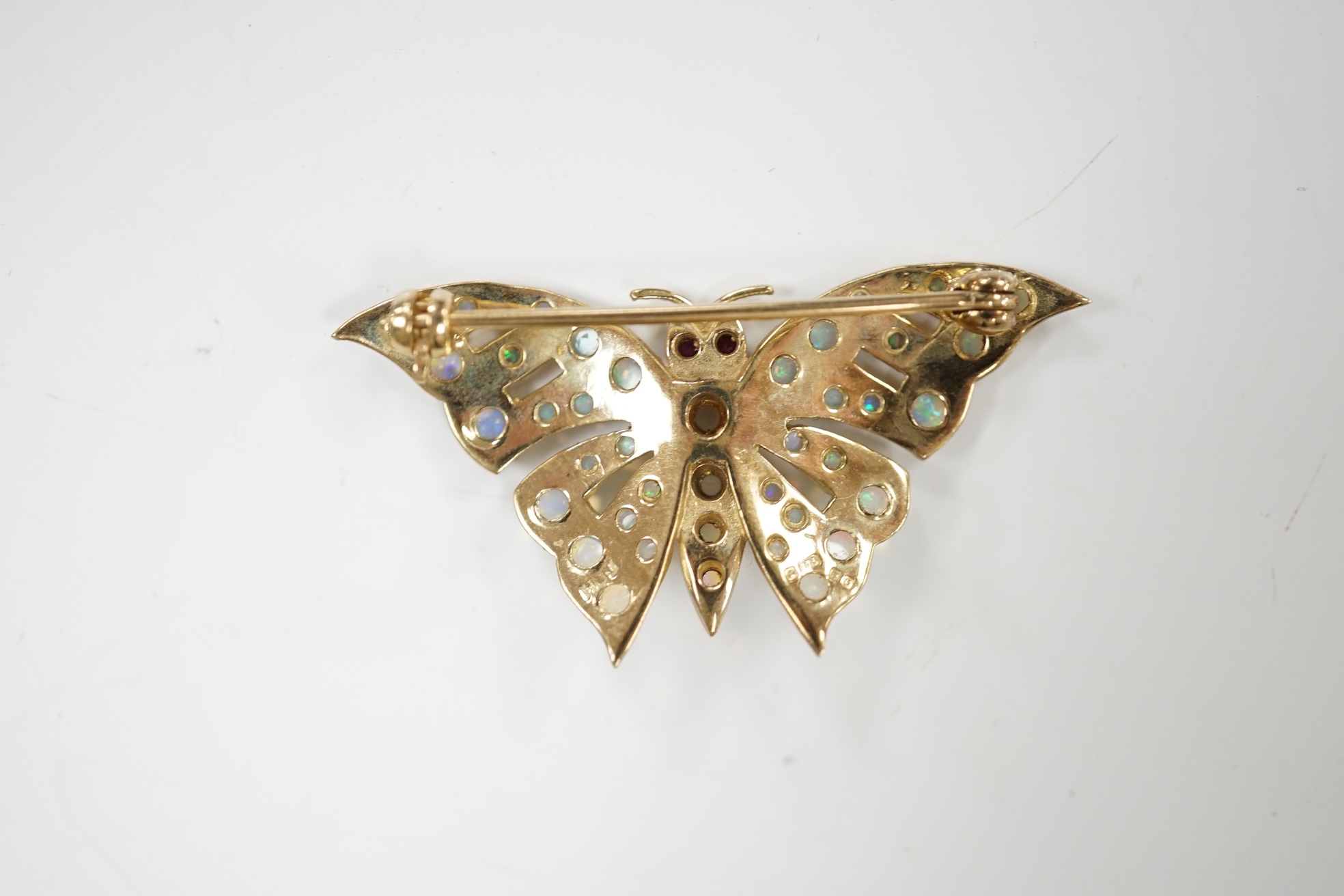 A modern 9ct gold and opal cluster set butterfly brooch, with ruby eyes, width 40mm, gross weight 4.8 grams. Condition - good